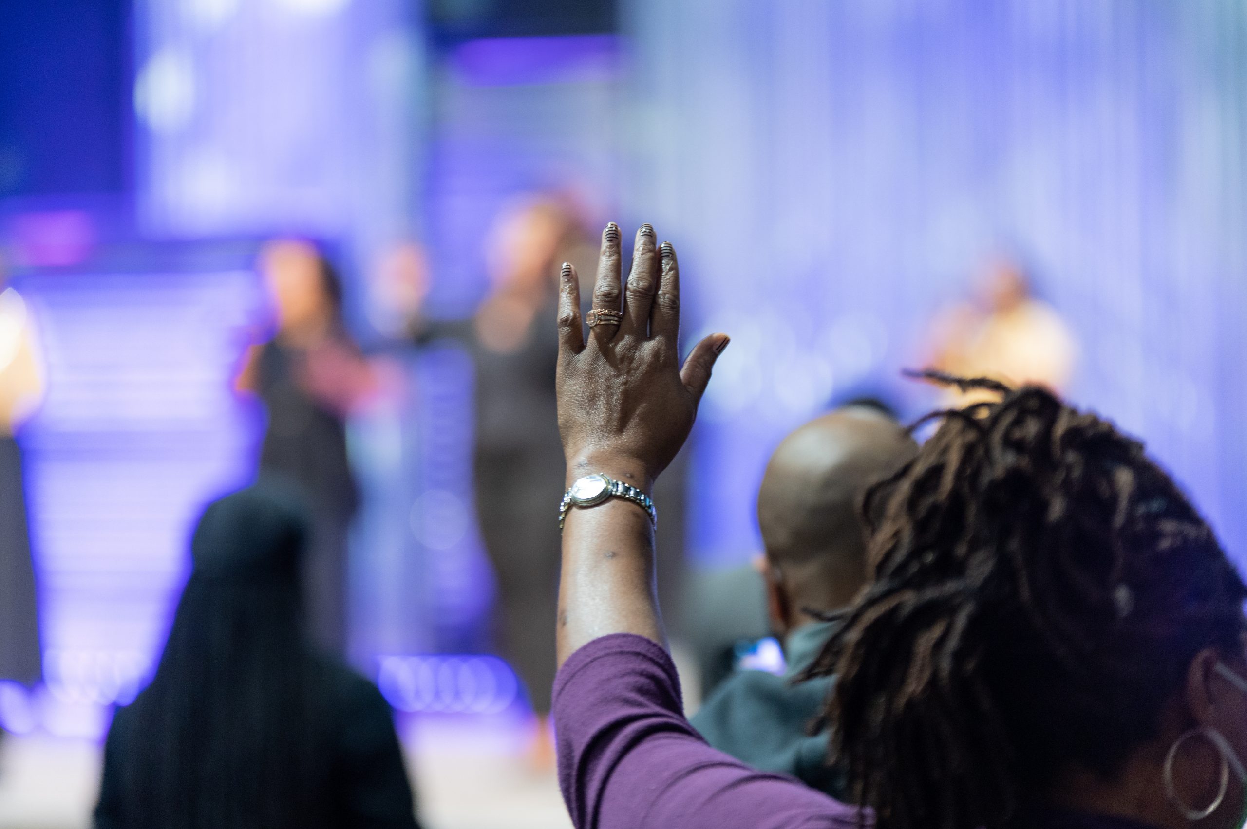 African American Woman in a Red Dress with Her Hand Raised in Ch